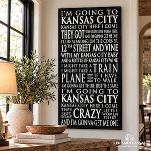 Puede incluir: Un lienzo rectangular negro para pared con texto blanco que incluye la letra de la canción Kansas City, con frases como I'm going to Kansas City, 12th Street and Vine, y I might take a train, plane, or if I have to walk.