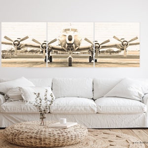 Puede incluir: Una impresi&oacute;n en lienzo vintage de tres paneles de un avi&oacute;n plateado en una pista. El avi&oacute;n tiene dos h&eacute;lices en cada ala y est&aacute; mirando hacia la c&aacute;mara. La imagen est&aacute; en tonos sepia.