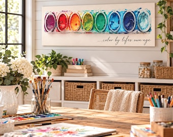 May include: A rectangular wall canvas featuring a horizontal row of eight vibrant watercolor paint pans in a rainbow gradient, with the black cursive text "...color by lifes own age" printed below the paint palette illustration.