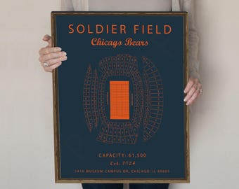 May include: A navy blue and orange print of Soldier Field, home of the Chicago Bears. The print shows the seating chart of the stadium with the field in the centre. The text "Soldier Field" and "Chicago Bears" is printed in orange at the top of the print. The text "Capacity: 61,500" and "Est. 1924" is printed in orange at the bottom of the print.