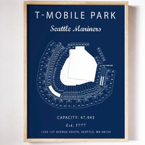 May include: A framed wall print featuring a dark blue background with a white diagram of T-Mobile Park, home of the Seattle Mariners. The text includes the stadium name, capacity of 47,943, established year 1999, and the address 1250 1st Avenue South, Seattle, WA 98134.