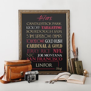 May include: A black framed chalkboard with gold lettering lists facts about the San Francisco 49ers football team. The text includes "Candlestick Park", "Tailgating", "Sourdough Sam", "5 Time Superbowl Champs", "Touchdown Gold Rush", "Cardinal & Gold", "Jerry Rice NFL", "NFC Joe Montana", "San Francisco", and "Linfor".