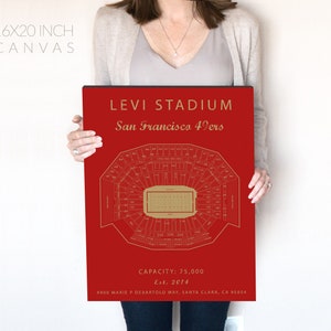May include: A red canvas print of Levi's Stadium, home of the San Francisco 49ers. The print features a detailed map of the stadium with the field and seating sections. The text "Levi Stadium" and "San Francisco 49ers" is printed in gold at the top of the print. The text "Capacity: 75,000" and "Est. 2014" is printed in gold at the bottom of the print.