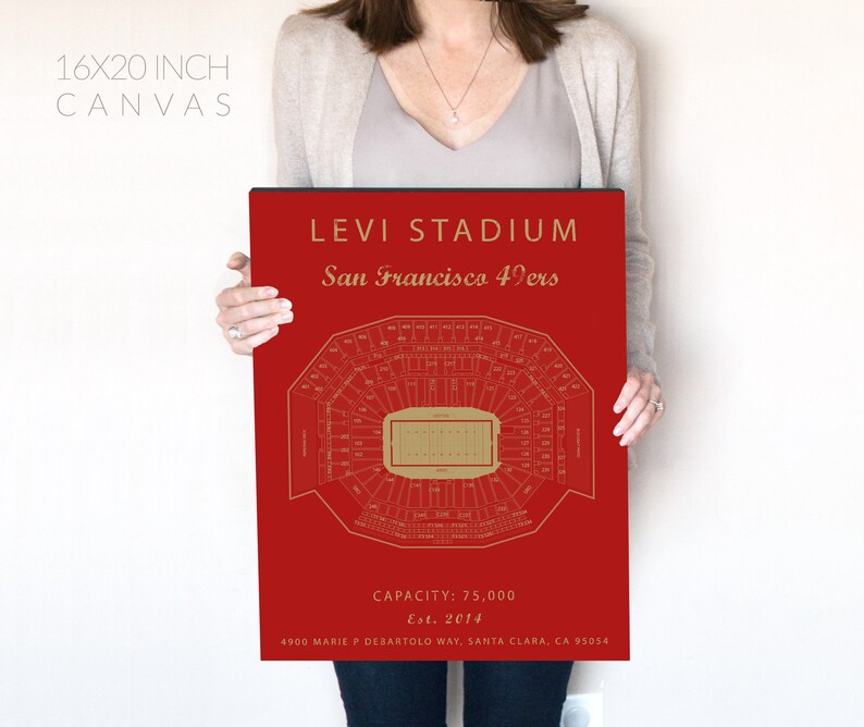 May include: A red canvas print of Levi's Stadium, home of the San Francisco 49ers. The print features a detailed map of the stadium with the field and seating sections. The text "Levi Stadium" and "San Francisco 49ers" is printed in gold at the top of the print. The text "Capacity: 75,000" and "Est. 2014" is printed in gold at the bottom of the print.