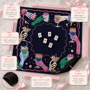 May include: A square dark blue mahjong mat featuring a colorful graphic print of skeletal and monster hands holding various cocktail glasses. The mat includes five white mahjong tiles in the center and four clear tile racks with pink tiles.