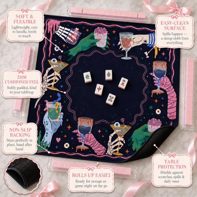 May include: A square dark blue mahjong mat featuring a colorful graphic print of skeletal and monster hands holding various cocktail glasses. The mat includes five white mahjong tiles in the center and four clear tile racks with pink tiles.