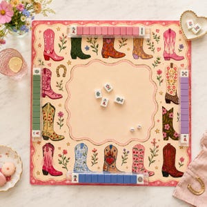 May include: A square mahjong game board featuring a cream-colored center and a border decorated with various colorful cowboy boot illustrations, floral motifs, and hearts. Four clear tile racks hold pink, green, purple, and blue tiles.