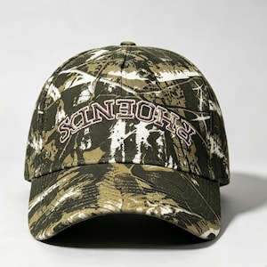 May include: A baseball cap featuring a camouflage pattern in shades of dark green, olive, and white. The front panel displays the word PHOENDS embroidered in a curved, brown-outlined font. The cap has a structured crown and a curved brim.