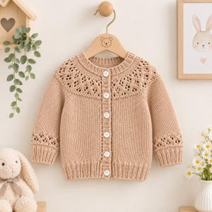 Può includere: Un cardigan in maglia a maniche lunghe color marrone chiaro con un motivo a rombi traforato sullo sprone e sui polsini. Il capo presenta un'abbottonatura verticale a coste con sei bottoni bianchi e un orlo a coste.