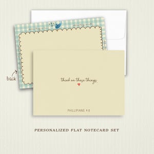 May include: A cream-colored flat notecard with the text 'think on these things.' and a small red heart, followed by 'PHILLIPIANS 4:8'. The back features a light blue gingham border, a scalloped edge, and a small blue bird illustration.