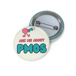 May include: A round pin-back button with an off-white background featuring a pink cartoon character holding a blue megaphone. The text reads ASK ME ABOUT in pink and PMOS in large, bold blue letters. The back shows a silver metal pin mechanism.