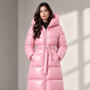 Peut inclure: Un long manteau doudoune rose clair brillant doté d'un col montant, d'une capuche et d'une ceinture à nouer assortie. Le manteau présente une fermeture éclair intégrale sur le devant, des manches longues et un matelassage horizontal.