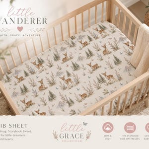 May include: A crib sheet featuring a repeating pattern of deer, pine trees, and mountains on a cream background. The text "little WANDERER" and "FAITH. GRACE. ADVENTURE." appears at the top, with "CRIB SHEET" and "little GRACE COLLECTION" below.