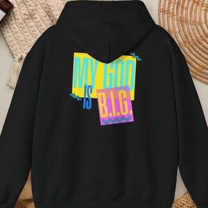 May include: A black hooded sweatshirt featuring a graphic on the back with the text "MY GOD IS B.I.G." in light blue and orange letters. The design includes a yellow rectangular background and a purple square with a zigzag pattern.