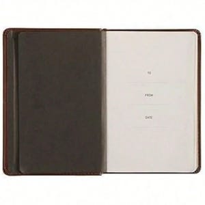 Puede incluir: Un cuaderno abierto con una cubierta de color marr&oacute;n oscuro y una solapa interior del mismo color en el lado izquierdo. La p&aacute;gina derecha es de color blanco roto y presenta el texto impreso TO, FROM y DATE, con l&iacute;neas para escribir.