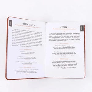 Puede incluir: Un libro devocional abierto con p&aacute;ginas blancas y texto negro. La p&aacute;gina izquierda se titula Fresh Start para el 1 de enero y la derecha se titula Vision para el 2 de enero. Ambas p&aacute;ginas contienen p&aacute;rrafos de texto, citas y encabezados.