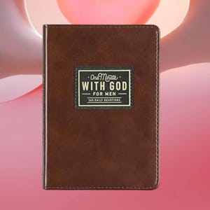 Puede incluir: Un libro de devociones rectangular de color marr&oacute;n con una cubierta lisa similar al cuero. Centrada en la parte frontal hay una etiqueta rectangular negra con texto en blanco y dorado: One Minute WITH GOD FOR MEN 365 DAILY DEVOTIONS. Bordes cosidos.