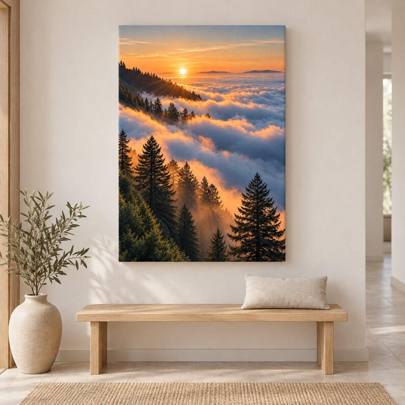 May include: A vertical wall art print depicting a mountain forest landscape at sunset. The scene features tall evergreen trees silhouetted against a bright orange sun, with thick, rolling clouds filling the valley below in warm golden light.