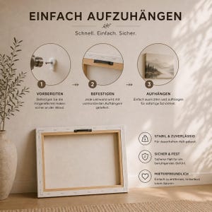 May include: An instructional graphic titled EINFACH AUFZUH&Auml;NGEN showing three steps for wall mounting a canvas. It features a rectangular canvas frame with a pre-installed black metal hanger on the back and icons for stability, security, and renter-friendly use.