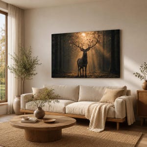 Op de afbeelding: Een rechthoekige wandkunstprint met een donker boslandschap en een centraal hert dat tussen zonnestralen staat. Het hert heeft een groot gewei versierd met kleine roze bloemen. Het kunstwerk hangt boven een beige bank in een woonkamer.