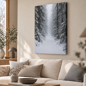 May include: A rectangular canvas wall art print featuring a vertical perspective of a snow-covered forest path. Tall, dark evergreen trees heavily laden with white snow line both sides of a narrow, misty trail leading into the distance.