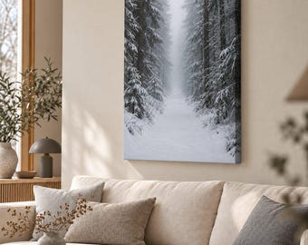 May include: A rectangular canvas wall art print featuring a vertical perspective of a snow-covered forest path. Tall, dark evergreen trees heavily laden with white snow line both sides of a narrow, misty trail leading into the distance.