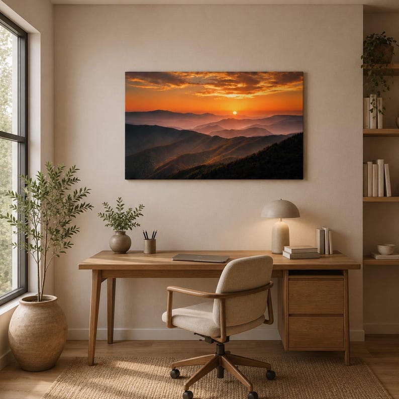 K&ouml;nnte beinhalten: Ein rechteckiger Wandkunstdruck, der einen Sonnenuntergang &uuml;ber geschichteten Gebirgsz&uuml;gen in Orange-, Gold- und tiefen Violettt&ouml;nen zeigt. Die Landschaft stellt einen dunstigen Horizont dar, wobei die Sonne tief am Himmel steht.