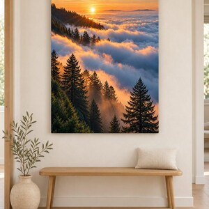 May include: A rectangular wall art print featuring a landscape of a dense evergreen forest on a mountainside during sunset. The sun glows orange above a thick layer of clouds that blankets the valley below, casting warm light on the pine trees.