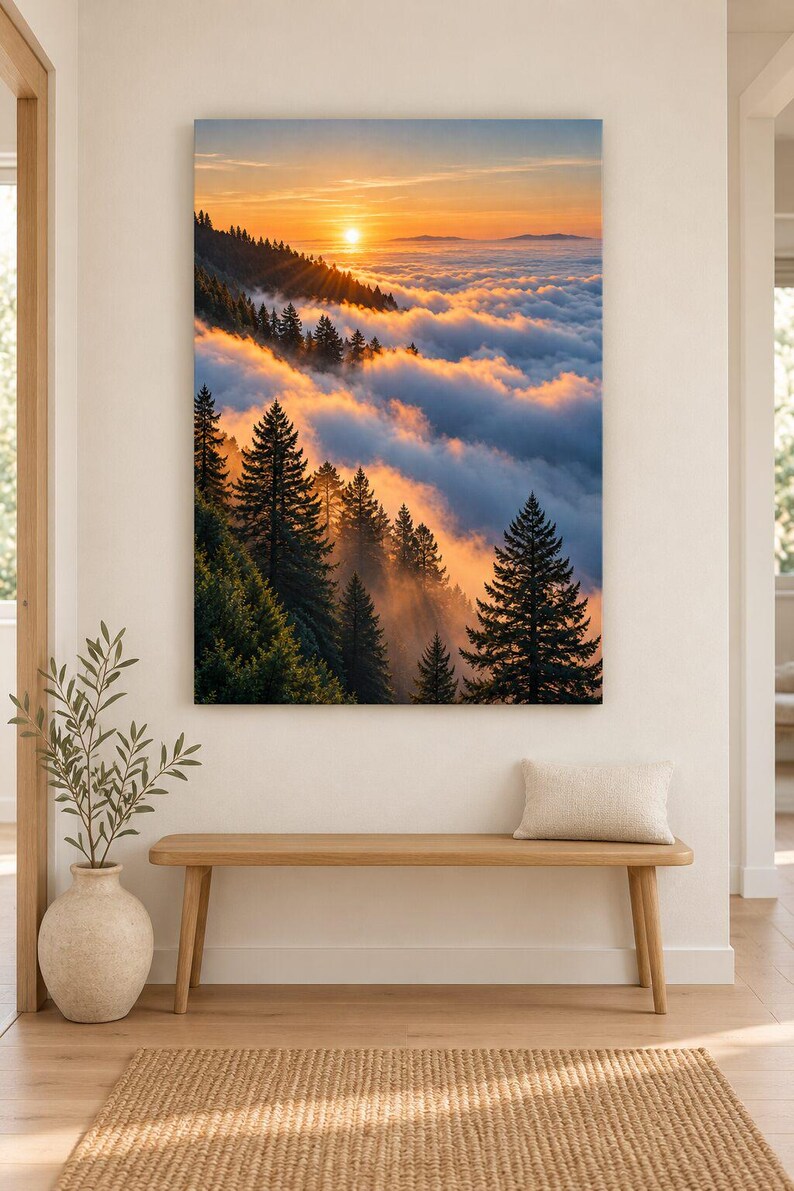 May include: A rectangular wall art print featuring a landscape of a dense evergreen forest on a mountainside during sunset. The sun glows orange above a thick layer of clouds that blankets the valley below, casting warm light on the pine trees.