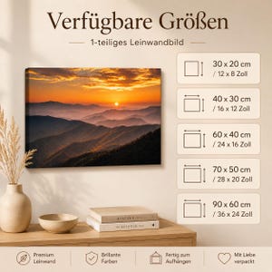 K&ouml;nnte beinhalten: Ein rechteckiger Leinwanddruck mit einem Sonnenuntergang &uuml;ber geschichteten Bergketten in Orange-, Gold- und Dunkelblaut&ouml;nen. Eine Tabelle listet die verf&uuml;gbaren Gr&ouml;&szlig;en in Zentimetern und Zoll auf: 30x20 cm, 40x30 cm, 60x40 cm, 70x50 cm und 90x60 cm.