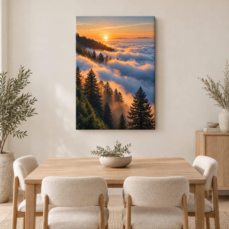 May include: A rectangular wall art print featuring a landscape of evergreen trees on a mountainside during sunset. The sun glows orange above a thick layer of clouds that fills the valley, casting warm light on the dark green pine tree silhouettes.