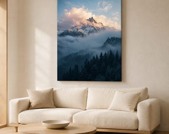 May include: A vertical rectangular wall art print featuring a snow-capped mountain peak partially obscured by soft pink and white clouds. Below the mountain, a dense forest of dark green pine trees is shrouded in a thick, low-hanging blue mist.