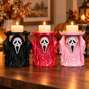 Peut inclure: Trois bougeoirs en forme de personnages vêtus de robes à capuche avec des masques de fantôme blancs, chacun doté d'une plateforme circulaire supérieure supportant une bougie pilier blanche allumée. Les figurines sont noires, rouges et rose clair.