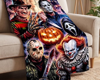 May include: A soft throw blanket featuring a vibrant, colourful illustration of five iconic horror movie characters, including a man in a fedora with clawed hands, a masked figure with a knife, a ghost-faced figure, a hockey-masked killer, and a clown.