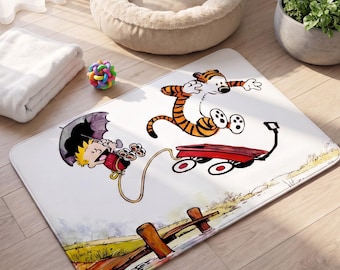 May include: A rectangular area rug featuring a white background with a colourful illustration of a boy holding a black umbrella and a tiger jumping over a red wagon. The bottom of the rug shows a painted landscape with a wooden fence and grass.