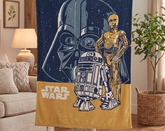 May include: A rectangular fleece throw blanket featuring a dark blue starry background with a large Darth Vader helmet graphic. In the foreground, C-3PO and R2-D2 stand on a mustard yellow base with the white Star Wars logo printed.