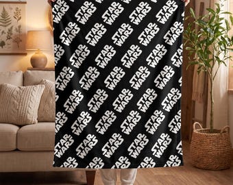 May include: A black fleece blanket featuring a repeating white Star Wars logo pattern arranged in diagonal rows across the entire surface. The fabric displays the iconic text in a bold, sans-serif font, creating a high-contrast graphic design.