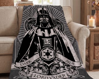 May include: A grey and black fleece throw blanket featuring a graphic illustration of Darth Vader. The design includes the Galactic Empire symbol, ornate scrollwork, and the text "DARK SIDE" and "LORD VADER" printed in a bold font.