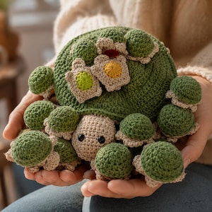 Pode incluir: Um brinquedo de tartaruga em crochê com um casco verde-escuro adornado com pequenos detalhes redondos em forma de cogumelo verde e três pequenas aplicações planas em forma de flor nas cores verde-claro, amarelo e vermelho. A cabeça é bege com olhos pretos.