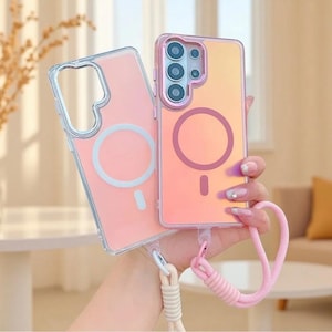 May include: Two rectangular smartphone cases with iridescent finishes. One case is clear with a white circular magnetic ring, and the other has a pinkish hue with a dark pink magnetic ring. Both feature attached woven wrist straps in light colours.