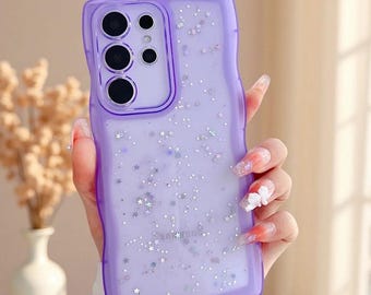 May include: A translucent purple phone case with a wavy edge design, featuring a scattered pattern of small silver star-shaped glitter and tiny reflective dots throughout the back panel, designed for a device with a multi-lens camera array.