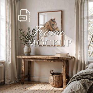 May include: A rectangular wooden picture frame hanging on a wall, containing an illustration of a brown horse wearing a bridle. The frame is positioned above a rustic wooden console table with a ceramic vase, a woven basket, and stacked books.
