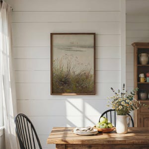 May include: A rectangular framed wall art piece featuring a muted landscape painting of wild grasses and foliage under a soft, hazy sky. The artwork is enclosed in a simple dark wood frame and is displayed on a white horizontal plank wall.