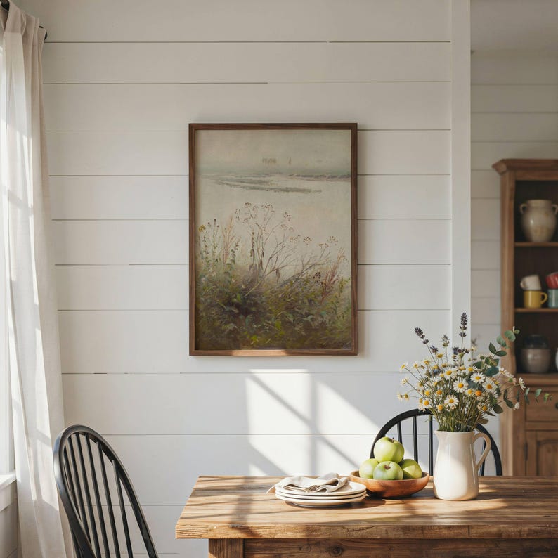 May include: A rectangular framed wall art piece featuring a muted landscape painting of wild grasses and foliage under a soft, hazy sky. The artwork is enclosed in a simple dark wood frame and is displayed on a white horizontal plank wall.