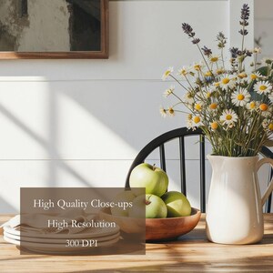 May include: A white ceramic pitcher filled with a bouquet of white daisies and purple lavender, placed next to a wooden bowl containing three green apples and a stack of white plates on a wooden table, with text reading High Quality Close-ups.