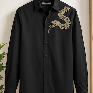 Può includere: Una camicia nera a maniche lunghe con bottoni e un grafico a forma di serpente dorato sulla parte superiore sinistra del petto. La camicia presenta un colletto standard, un'abbottonatura frontale e un'etichetta interna con la scritta EBFashionHub.
