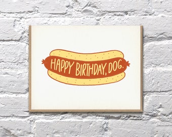 May include: A white card with a yellow and orange hot dog illustration. The text "Happy Birthday, Dog." is written on the hot dog.