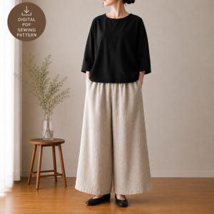 May include: A black top with three-quarter length sleeves and a round neckline paired with wide-leg beige trousers. The image includes a circular badge with the text DIGITAL PDF SEWING PATTERN. The outfit is shown in a neutral indoor setting.