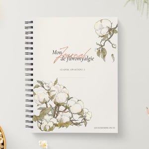 Puede incluir: Un diario de espiral con cubierta blanca que presenta ilustraciones en acuarela de ramas de algodón. El texto dice Mon Journal de fibromyalgie, Ce livre appartient à y Les Remembrances. El diseño incluye flores de algodón blancas.