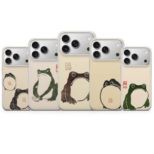 Peut inclure: Cinq coques de smartphone sur fond beige clair, chacune ornée d'une illustration de grenouille de style encre. Les motifs présentent diverses postures de grenouilles, certains avec de petits sceaux carrés rouges et un avec les caractères 問一 en rouge.